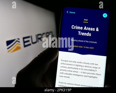 Person holding smartphone with webpage of EU law enforcement agency Europol on screen in front of logo. Focus on center of phone display. Stock Photo