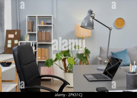 Side view at minimal home office workplace with laptop and high back chair, copy space Stock Photo