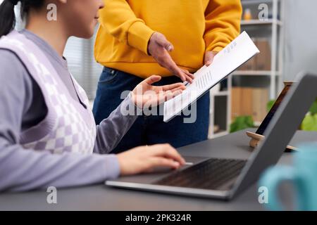 Closeup of two young people discussing document while collaborating on project Stock Photo