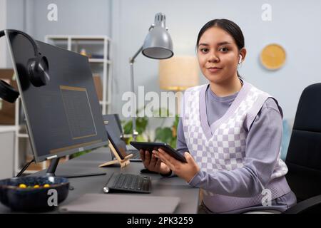 Portrait of young woman as female software developer looking at camera at workplace, copy space Stock Photo
