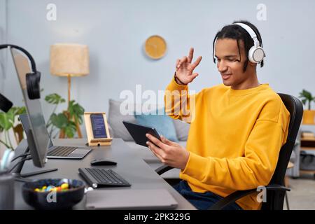 Portrait of black young man as software developer using digital tablet at workplace and smiling Stock Photo