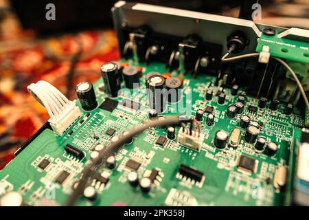 Paris, France - Mar 10, 2023: Close-up of multiple capacitors and transistors on a green board of a hi-fi system - circuit board and motherboard filled with various computer chips, representing the complex technology in the electronics industry Stock Photo