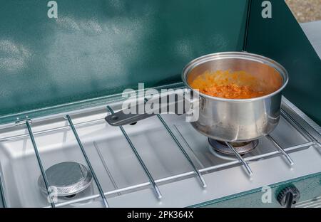 Cooking chili in a pot on an outdoor camp stove Stock Photo