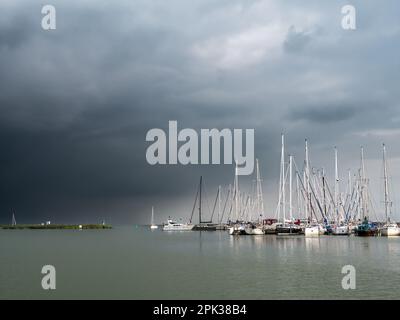 Threatening overcast sky with dark storm clouds over sailboats in marina, Enkhuizen, Noord-Holland, Netherlands Stock Photo