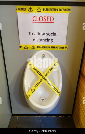 A urinal in a men's toilet that has been closed with tape to allow social distancing, England, UK Stock Photo