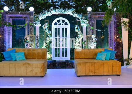 An elegantly staged traditional morocco style wedding with large sofa for the wedding couple to sit and receive blessings from the guests, surrounded Stock Photo