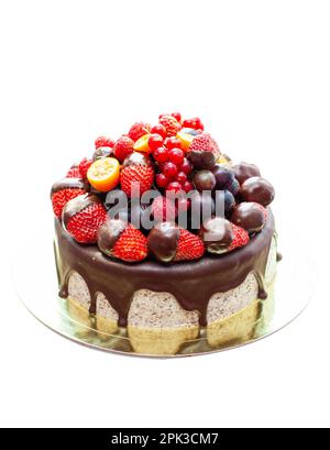 Cake decorated with strawberry dipped into melted chocolate, raspberry, blueberry and red currant. Isolated on plain background Stock Photo