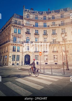 Lone man riding a bicycle near a crosswalk on the Paris city street in the morning, France Stock Photo