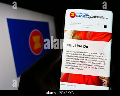 Person holding cellphone with webpage of Association of Southeast Asian Nations (ASEAN) on screen with logo. Focus on center of phone display. Stock Photo