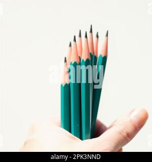 Green set of graphite pencils in hand. White wall background. Stock Photo