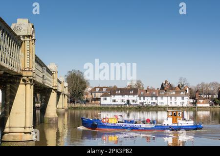 A Thames Marine Services boat passing the Bull's Head Public House and Kew Railway Bridge on the River Thames at Strand-on-the-Green, Chiswick, London Stock Photo