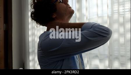 Tired man massaging stiff neck tensed muscles fatigued from computer work Stock Photo