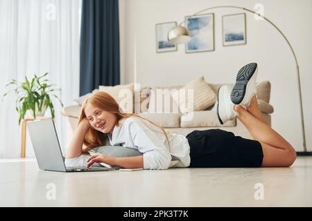 Modern technologies. Female teenager with blonde hair is at home at daytime Stock Photo