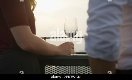 Woman holding red wine drinking wine with sunset on high building city view Stock Photo