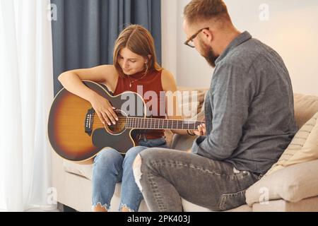 Guitar teacher showing how to play the instrument to young woman Stock Photo