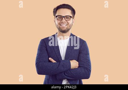 Happy young businessman in a dark suit stands with his arms crossed. Stock Photo