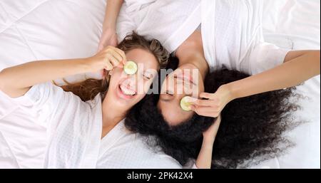 Two young attractive women in white bathrobes making facial mask Stock Photo