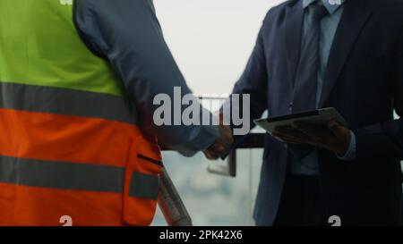 Construction workers shaking hands businesspeople at construction site Stock Photo