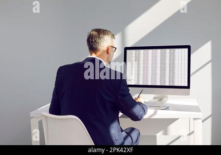 Businessman or accountant at workplace compares data on electronic spreadsheet on computer. Stock Photo