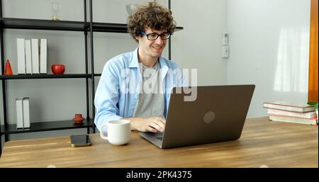 Smiling man with eyeglasses using laptop working at home Stock Photo