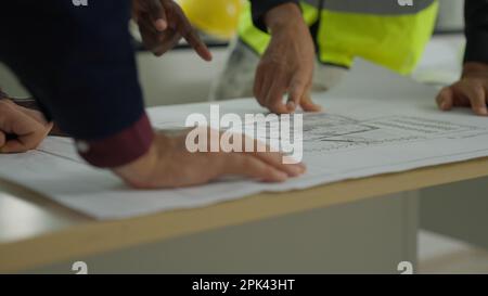 Close up blueprint, male engineer foreman using blueprint assigning work plan Stock Photo