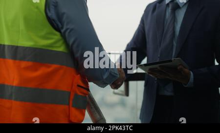 Construction workers shaking hands businesspeople at construction site Stock Photo