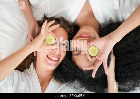 Two young attractive women in white bathrobes making facial mask Stock Photo