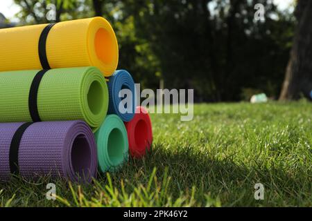 Bright exercise mats on fresh green grass outdoors, space for text Stock Photo