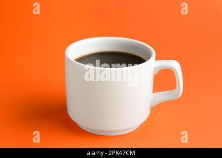 White mug of freshly brewed hot coffee on orange background Stock Photo