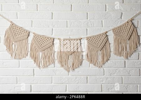 Stylish macrame hanging on white brick wall Stock Photo