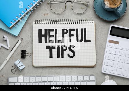 Flat lay composition with text Helpful Tips in notebook on grey table Stock Photo