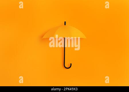 Bright toy umbrella on orange background, top view Stock Photo