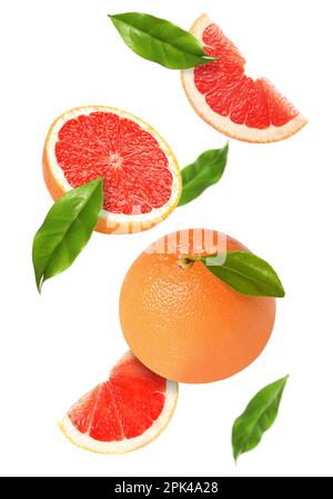 Tasty ripe grapefruits and green leaves falling on white background Stock Photo