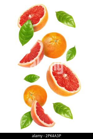 Tasty ripe grapefruits and green leaves falling on white background Stock Photo
