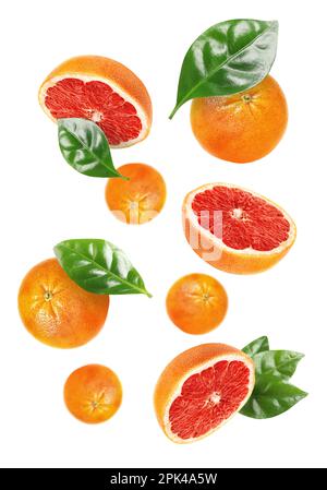 Tasty ripe grapefruits and green leaves falling on white background Stock Photo