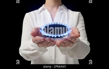 Closeup view of woman holding gas burner with blue flame on black background Stock Photo