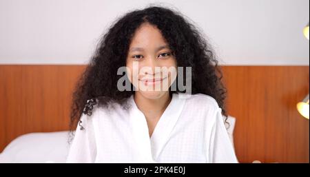 Portrait of young woman with curly hair in white bathrobe smiling Stock Photo