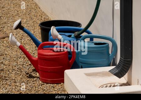 Langebaan, west coast, South Africa. 2023. Watering cans being filled from a hose and tap on a garden path. Stock Photo