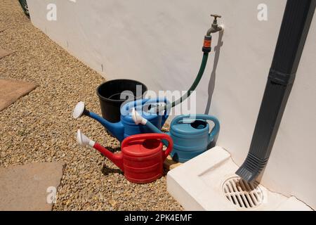 Langebaan, west coast, South Africa. 2023. Watering cans being filled from a hose and tap on a garden path. Stock Photo