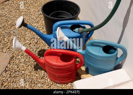 Langebaan, west coast, South Africa. 2023. Watering cans being filled from a hose and tap on a garden path. Stock Photo