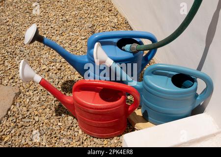 Langebaan, west coast, South Africa. 2023. Watering cans being filled from a hose and tap on a garden path. Stock Photo