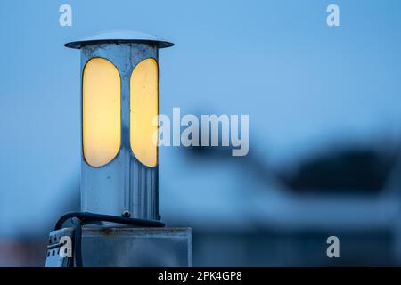 Circular lamp shining yellow in the dusk Stock Photo