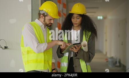 Engineers using tablet talking and brainstorming together on construction site Stock Photo