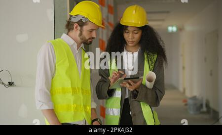 Engineers using tablet talking and brainstorming together on construction site Stock Photo