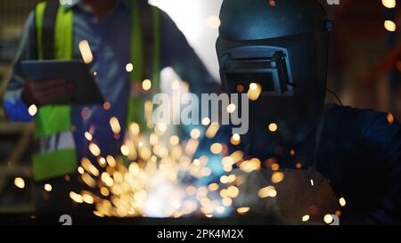 Welders welding steel in factory, Welders with protective mask Stock Photo