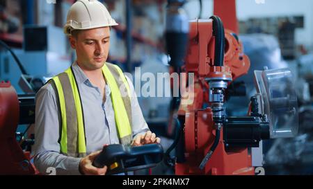 Engineer holding remote control controlling industrial machine in the factory Stock Photo