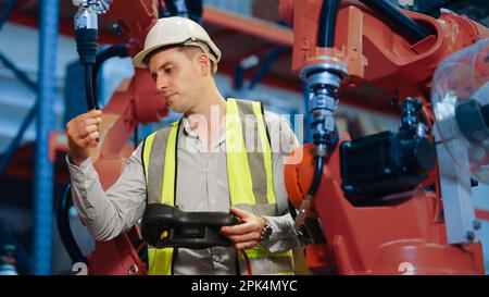 Engineer holding remote control controlling industrial machine in the factory Stock Photo