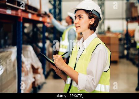 Warehouse supervisor using tablet for controlling and checking goods on shelves Stock Photo
