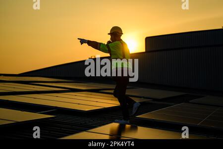 Engineer working at solar cell farm power plant with sunset in evening Stock Photo