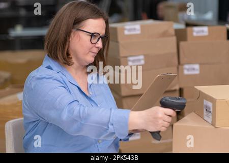 Online store workers scanning parcel boxes barcodes in their shop for tracking and shipping delivery Stock Photo